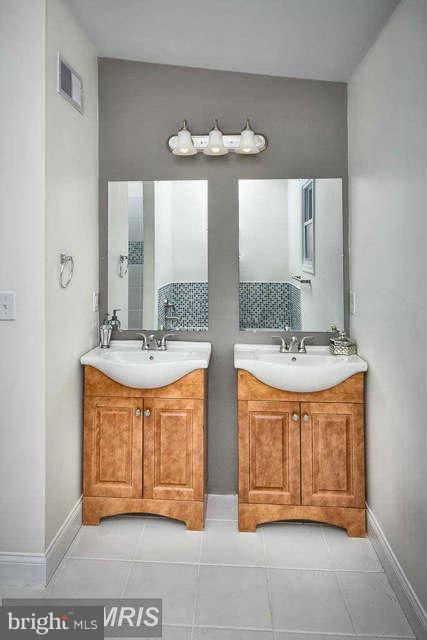 3616 Reisterstown Road Baltimore, MD 21215 - Photo 20 of 26 a bathroom with double vanity and a mirror