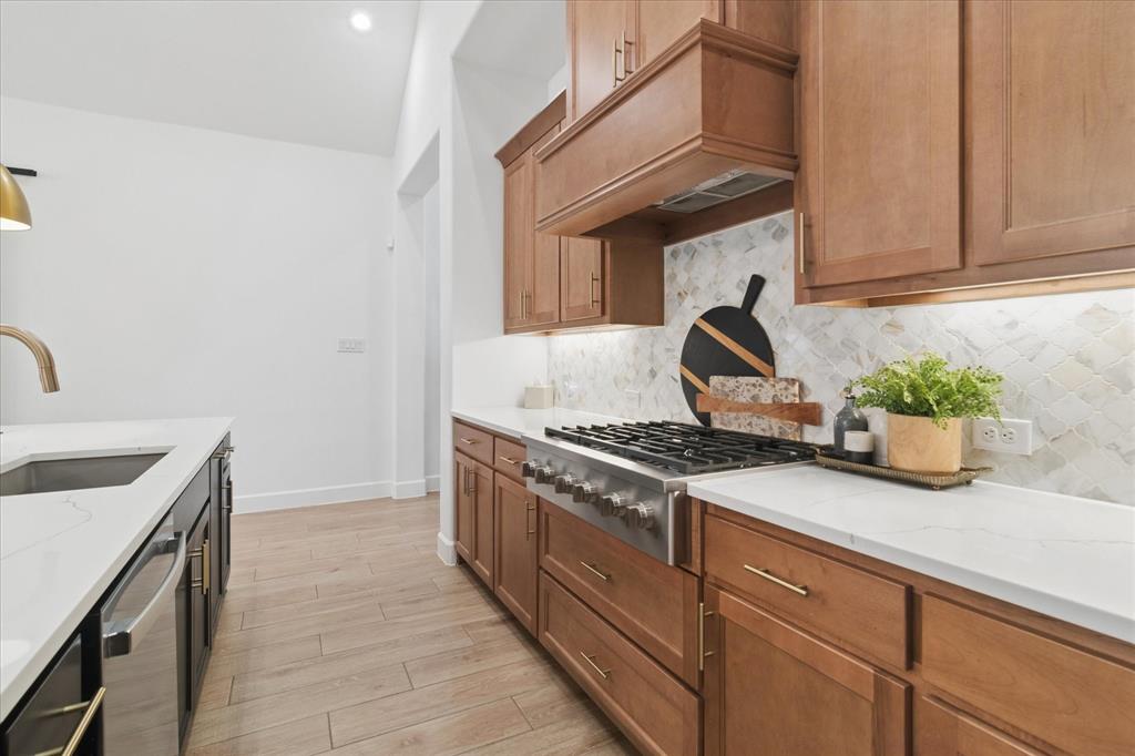 582 Broadleaf Way Haslet, TX 76052 - Photo 10 of 40 Gas cooktop with wood vented hood, white quartz countertops, marble tile backsplash.
