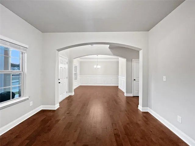 a view of an empty room with wooden floor fireplace and a window