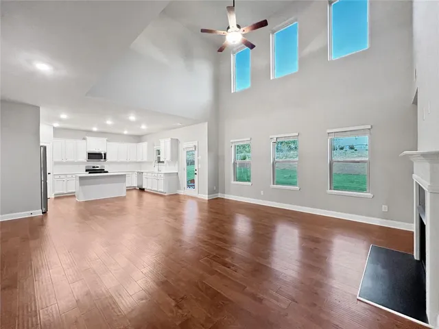 an empty room with windows fireplace and a kitchen view