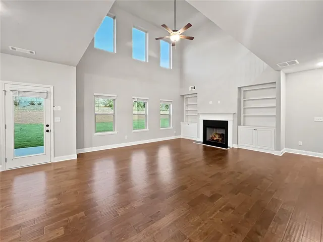 a view of an empty room with wooden floor fireplace and a window
