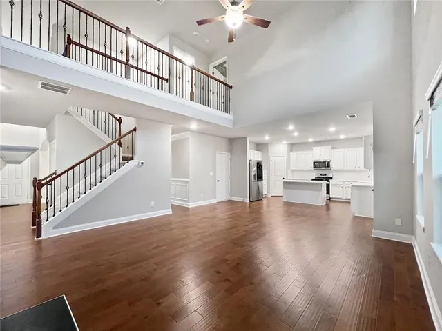 a view of an empty room with wooden floor a ceiling fan
