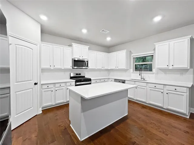 a kitchen with white cabinets and appliances