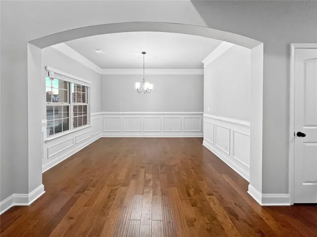 a view of a livingroom with wooden floor entryway and a kitchen space