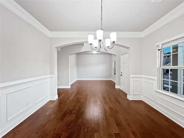 a view of empty room with wooden floor and chandelier