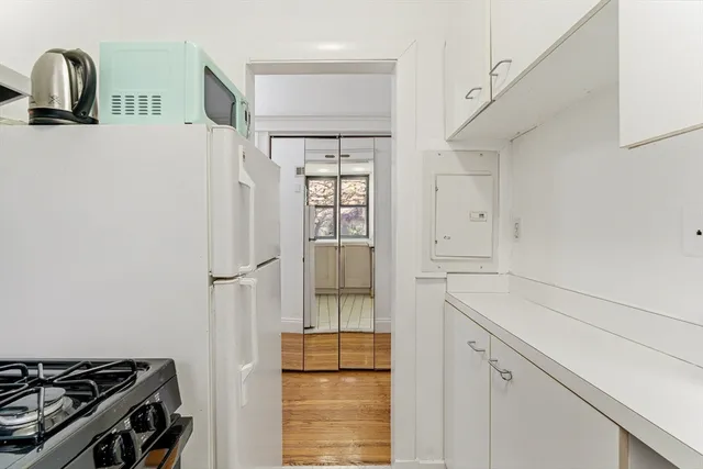 a kitchen with a refrigerator and white cabinets