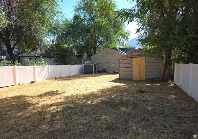 3161 Adams Avenue Ogden, UT 84403 - Photo 17 of 17 Expansive backyard featuring a white privacy fence, an accessory structure with horizontal siding, and mature trees providing shade