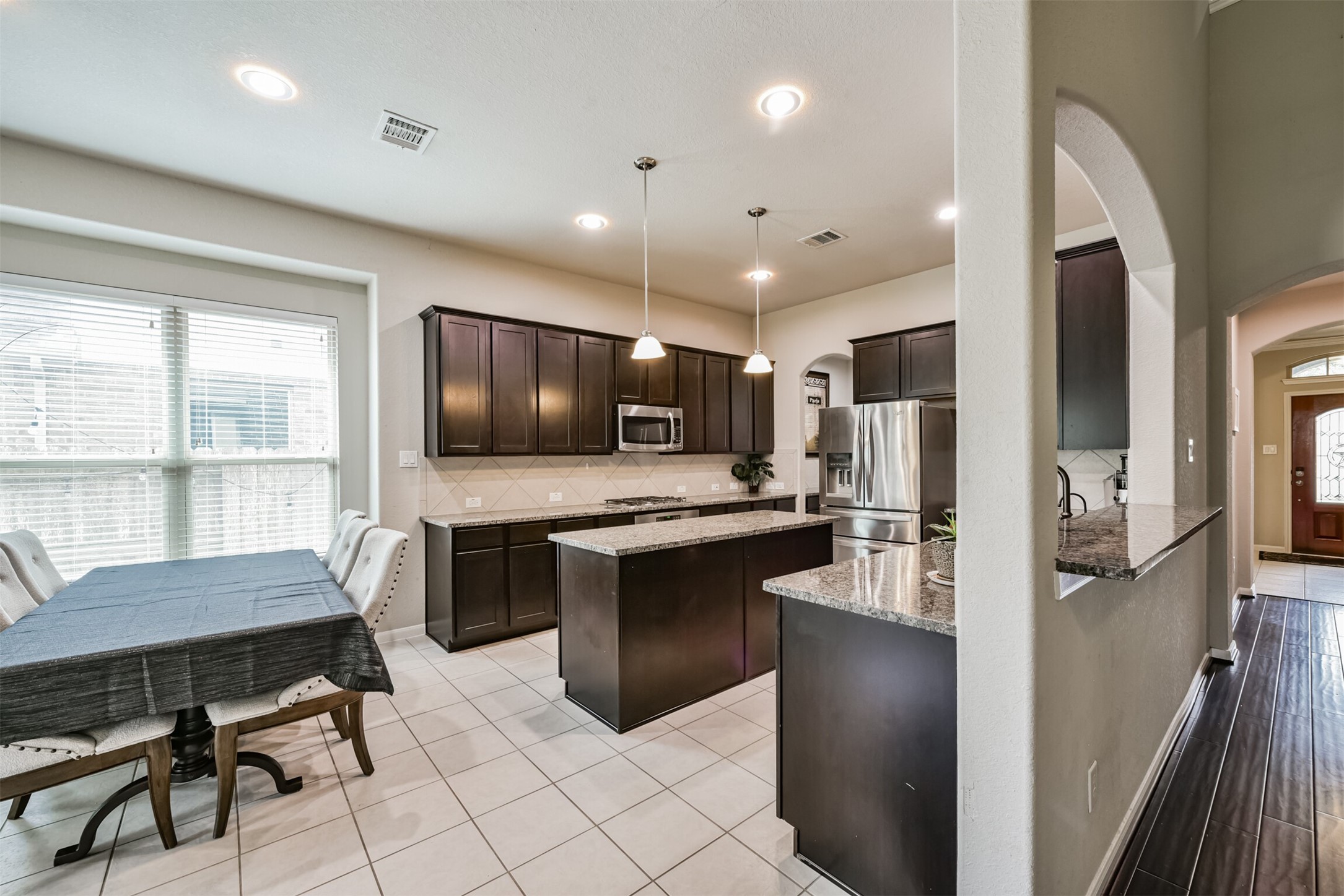 4827 Oak Rambling Drive Katy, TX 77494 - Photo 13 of 45 a kitchen with stainless steel appliances granite countertop a refrigerator a sink dishwasher a stove and a dining table with wooden floor