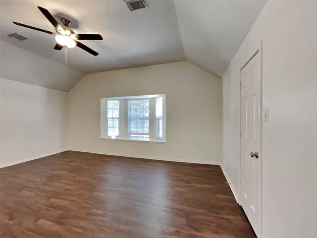 an empty room with wooden floor fan and windows