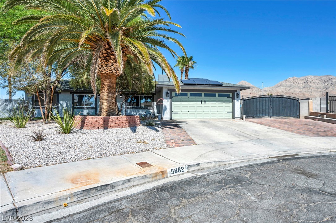 5882 Rio Tinto Way Las Vegas, NV 89110 - Photo 2 of 56 Mature palm trees adorn the front yard of this inviting single-story home, featuring a two-car garage and solar panels.