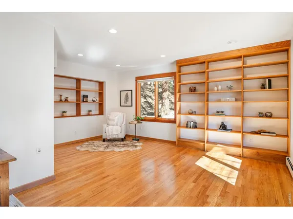 a view of an empty room with window and wooden floor