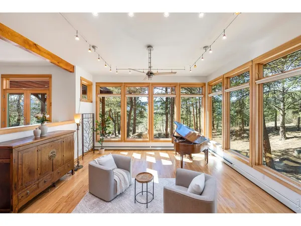 a living room with furniture large windows and wooden floor