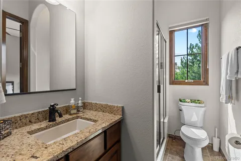 a bathroom with a granite countertop sink toilet and mirror