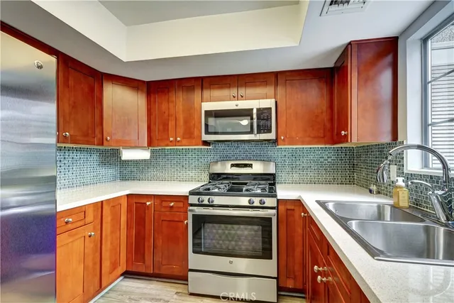 a kitchen with granite countertop wood cabinets stainless steel appliances and a sink