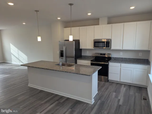 a kitchen with kitchen island granite countertop a sink a counter top space appliances and cabinets