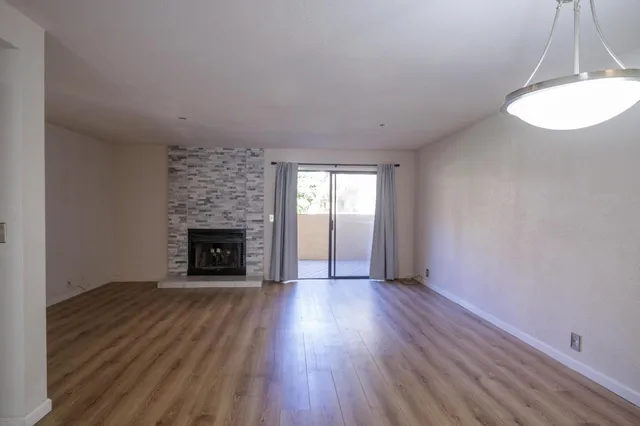 an empty room with wooden floor fireplace and window