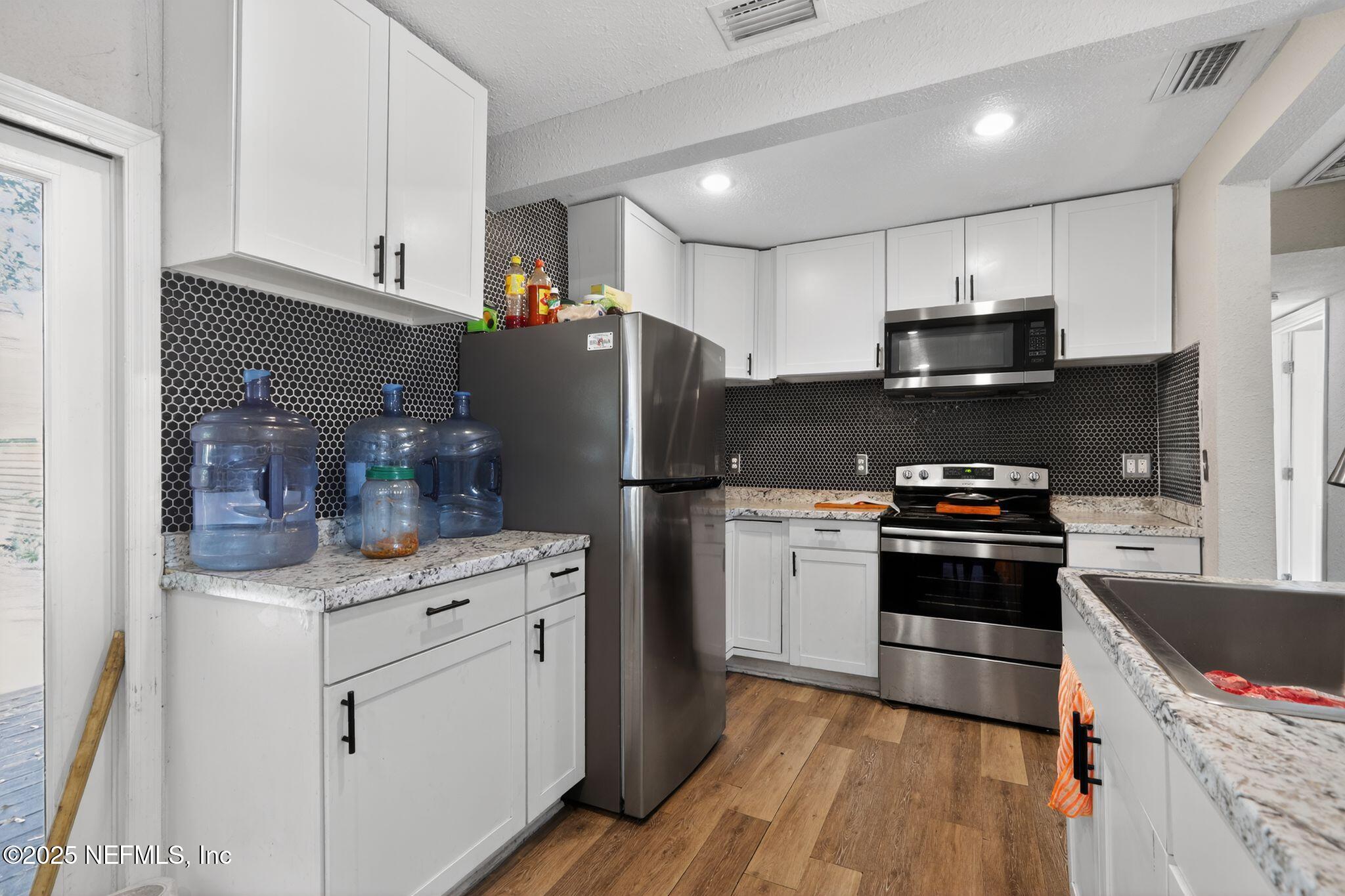 2181 West 17th Street Jacksonville, FL 32209 - Photo 11 of 27 a kitchen with a sink a refrigerator and a stove top oven with wooden floor