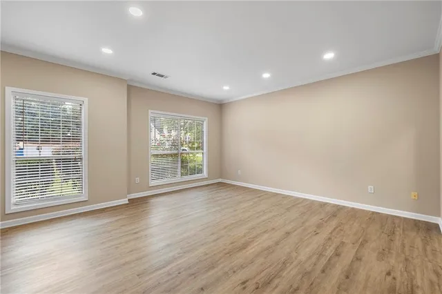 a view of an empty room with wooden floor and a window
