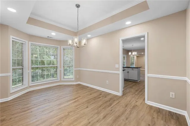 an empty room with wooden floor mirror and windows