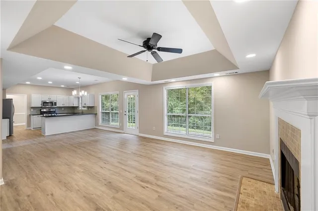 a view of an empty room with wooden floor and a kitchen