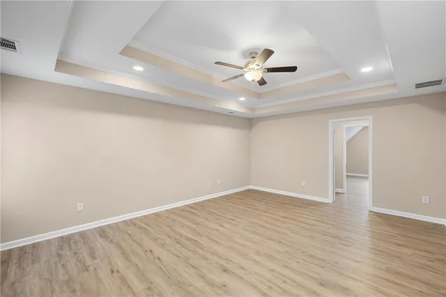 an empty room with wooden floor and a ceiling fan