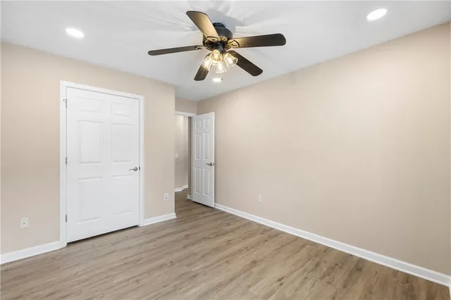 an empty room with wooden floor ceiling fan and windows
