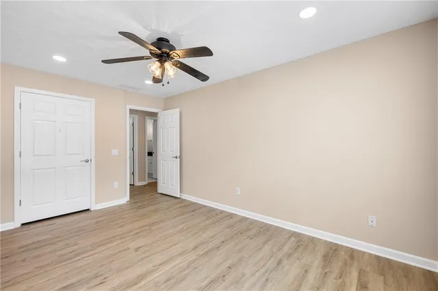 a view of an empty room with wooden floor and a ceiling fan