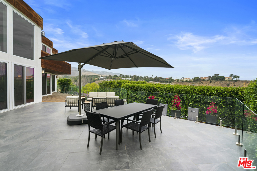 6272 Cavalleri Road Malibu, CA 90265 - Photo 40 of 47 a view of a dining table and chairs under an umbrella in patio of a house