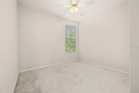 an empty room with a window and a ceiling fan