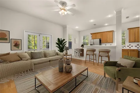 a living room with furniture kitchen view and a large window