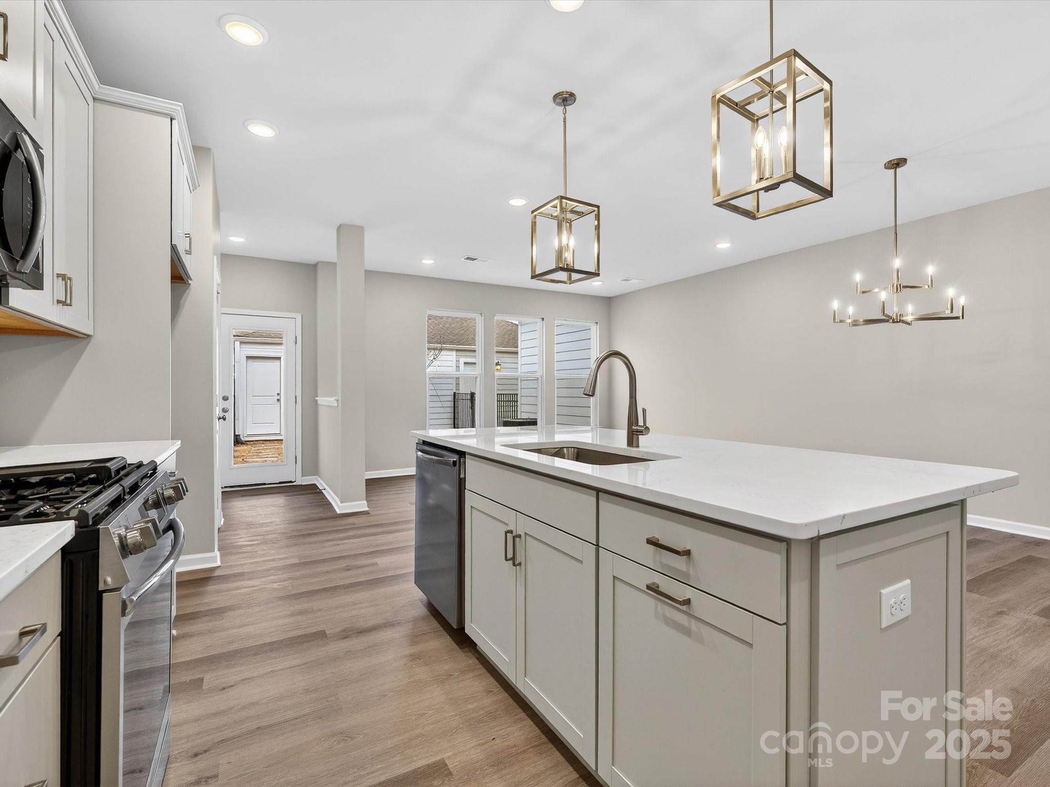 11439 Prosperity Church Road Huntersville, NC 28078 - Photo 8 of 34 a kitchen with a sink stainless steel appliances a chandelier and wooden floor