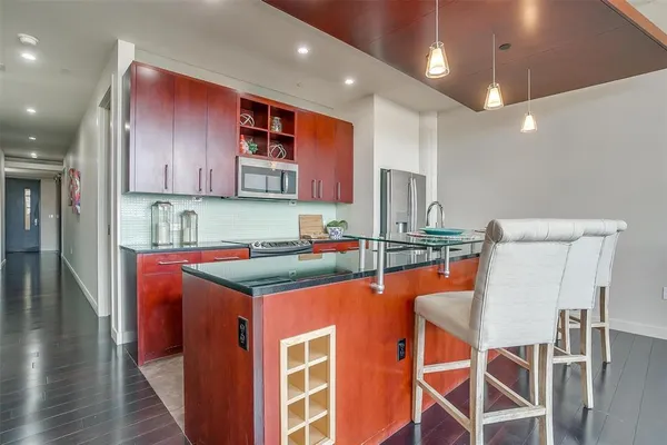 a kitchen with stainless steel appliances kitchen island granite countertop a dining table chairs sink and cabinets