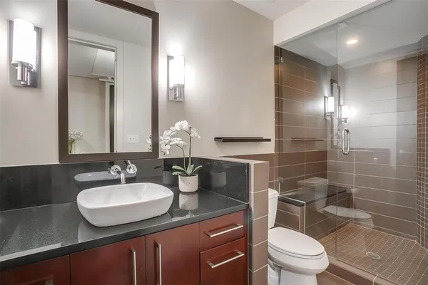 a bathroom with a granite countertop sink toilet a mirror and a shower