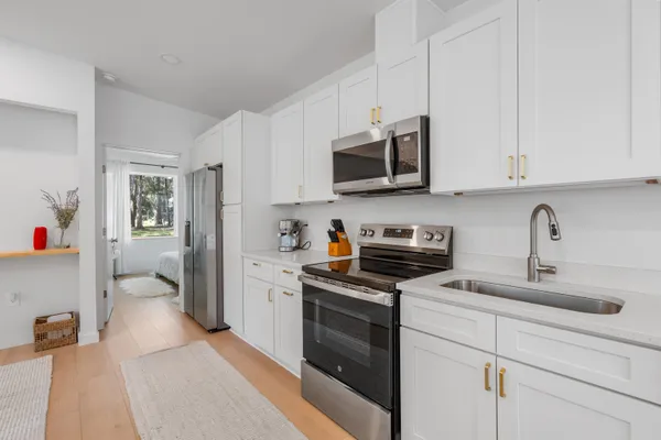 a kitchen with stainless steel appliances granite countertop a sink dishwasher stove and white cabinets