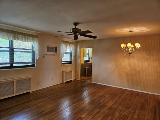 a view of a livingroom with a hardwood floor a ceiling fan and windows