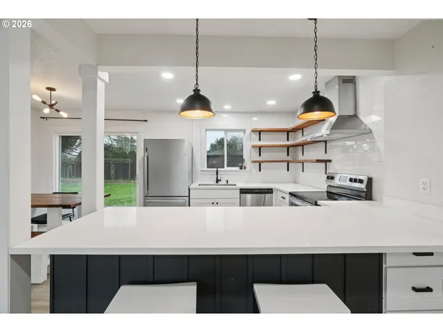 a kitchen with stainless steel appliances a sink a counter space a large window and chairs
