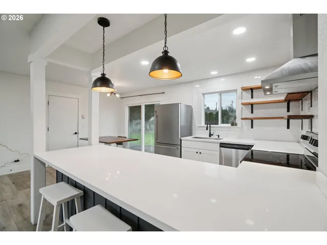 a room with stainless steel appliances kitchen island a table and chairs