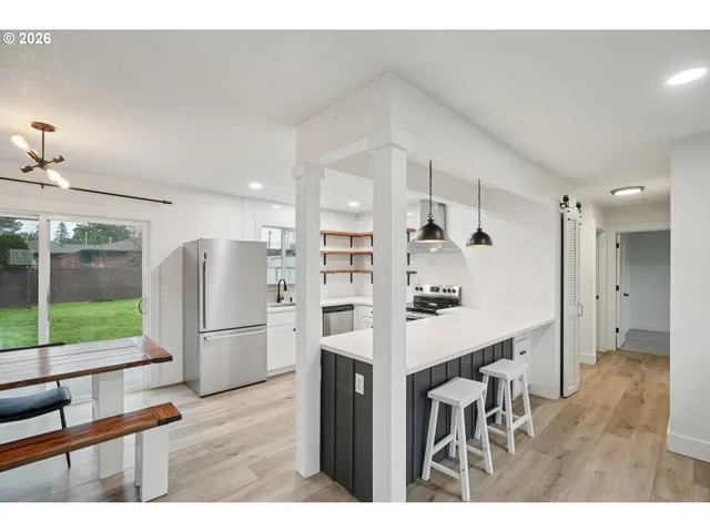a kitchen with stainless steel appliances a refrigerator and a wooden floor