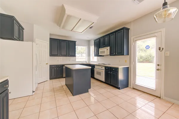 a large kitchen with stainless steel appliances granite countertop a stove a sink dishwasher a microwave oven and a refrigerator with wooden cabinets