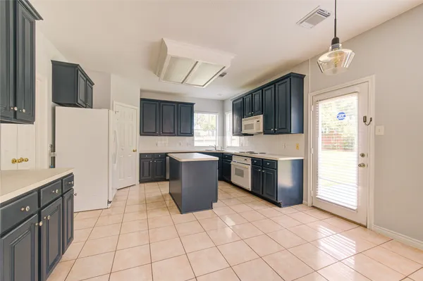 a large kitchen with stainless steel appliances granite countertop a stove top oven a sink dishwasher a dining table and chairs with wooden floor
