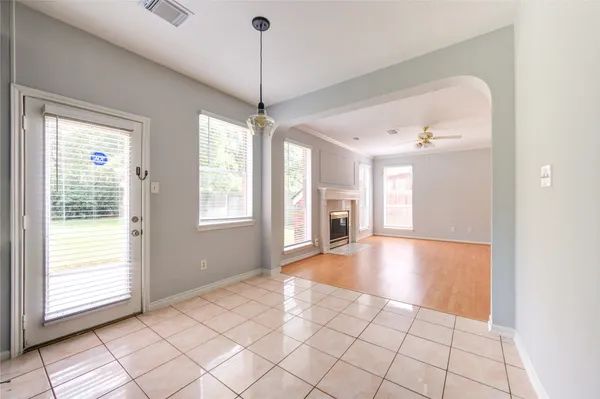 a view of an empty room with window and chandelier fan
