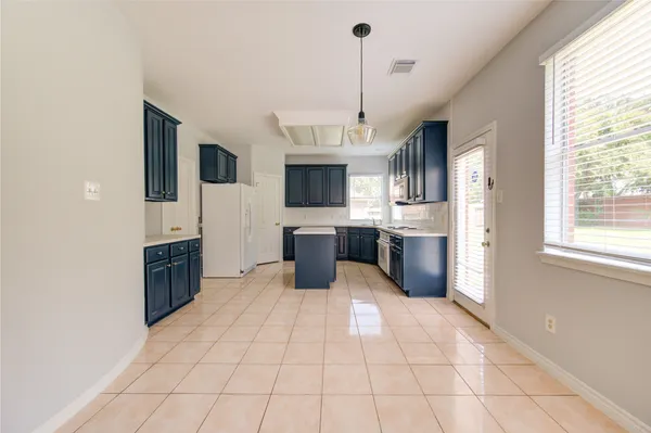 a large kitchen with cabinets a sink a window and stainless steel appliances