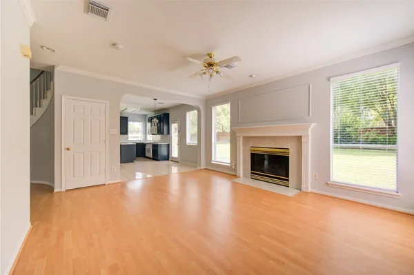 a view of a livingroom with a fireplace a ceiling fan and windows