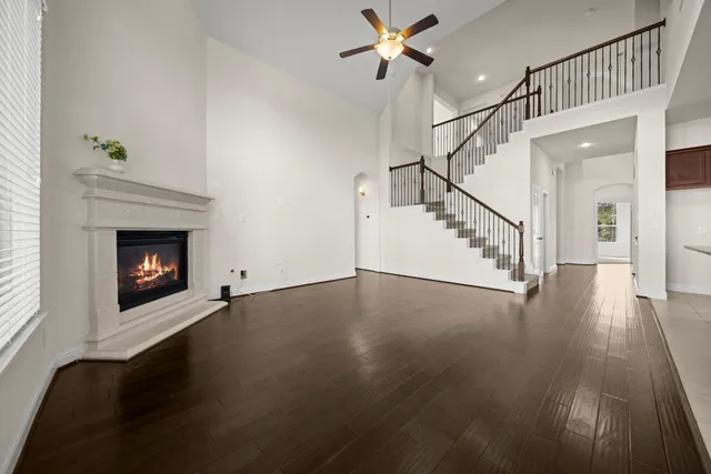 a view of an empty room with wooden floor fireplace and a window