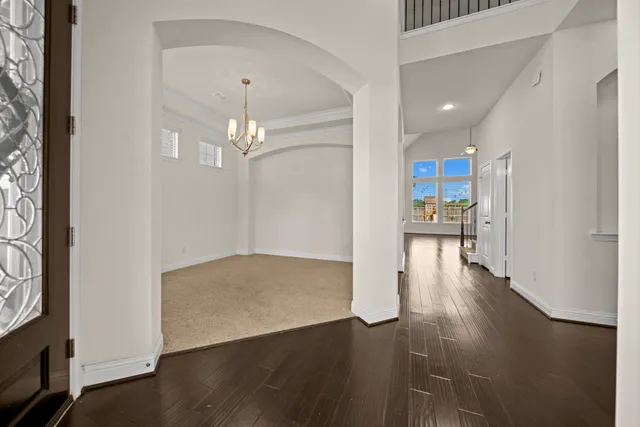 a view of a hallway with wooden floor and a kitchen