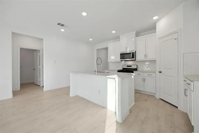 a kitchen with white cabinets and stainless steel appliances
