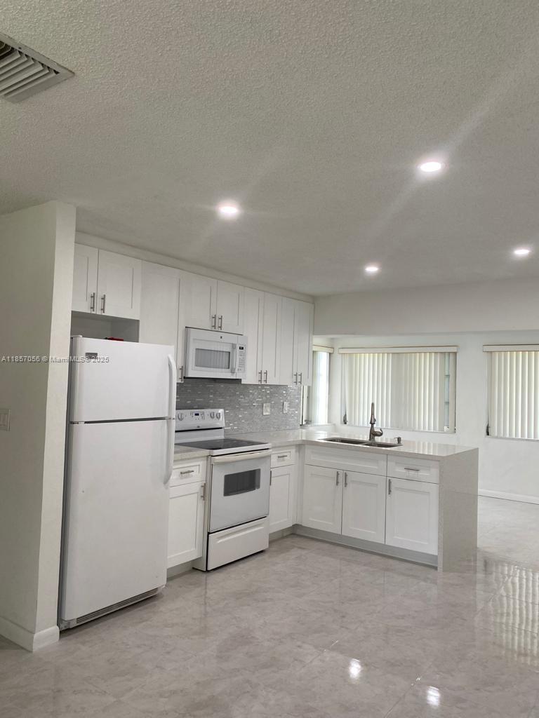 a kitchen with a sink a white refrigerator and white cabinets