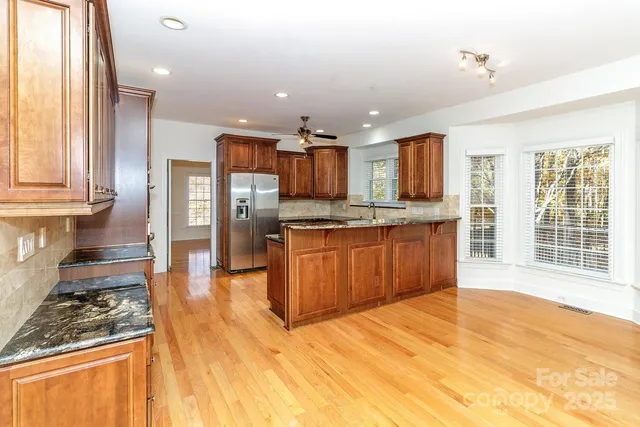 a kitchen with stainless steel appliances granite countertop a stove top oven a sink dishwasher a dining table and chairs with wooden floor