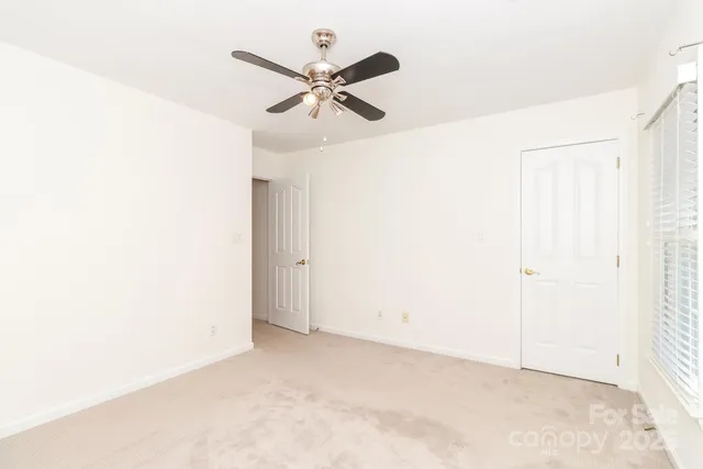 an empty room with ceiling fan and window