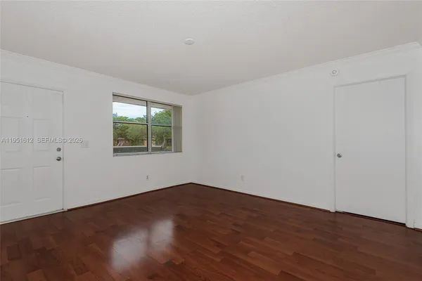 a view of an empty room with wooden floor and a window